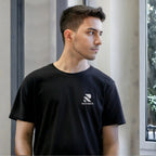 Man wearing a black Rovarix t-shirt with a logo, standing indoors.