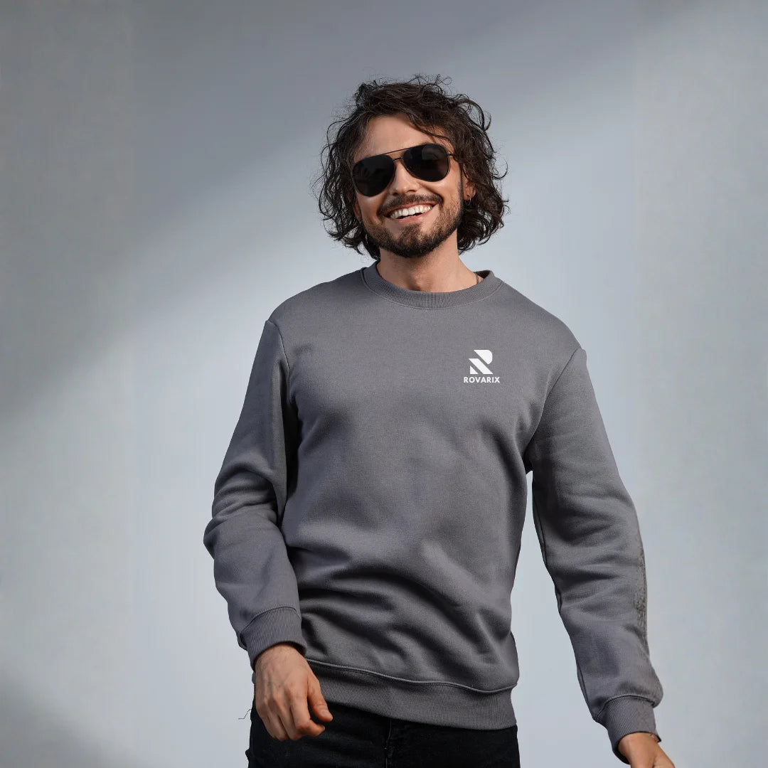 Man wearing a gray sweatshirt with a logo on a plain background