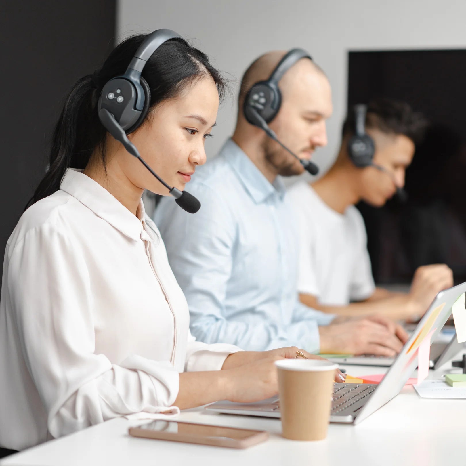 Call center agents wearing headsets and working on laptops.
