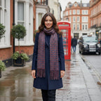 Woman wearing a navy blue wool coat styled with the Rovarix geometric patterned scarf on a city street.
