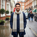 Man wearing a navy overcoat and beige plaid Rovarix scarf walking in a city street.