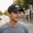 Man wearing a black cap with a Rovarix brand logo on a blurred street background