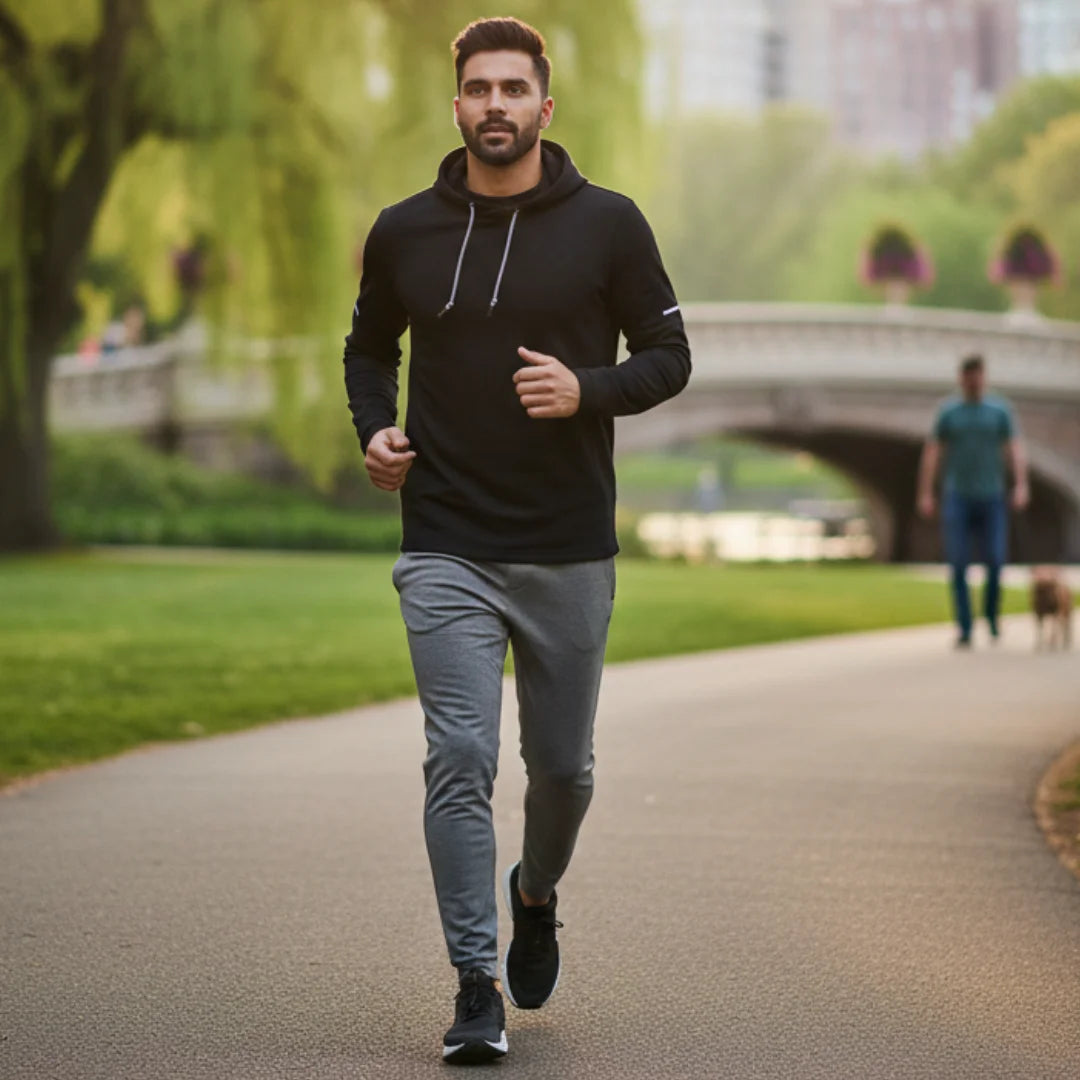 an wearing Rovarix black hoodie sweatshirt running through park with green trees 