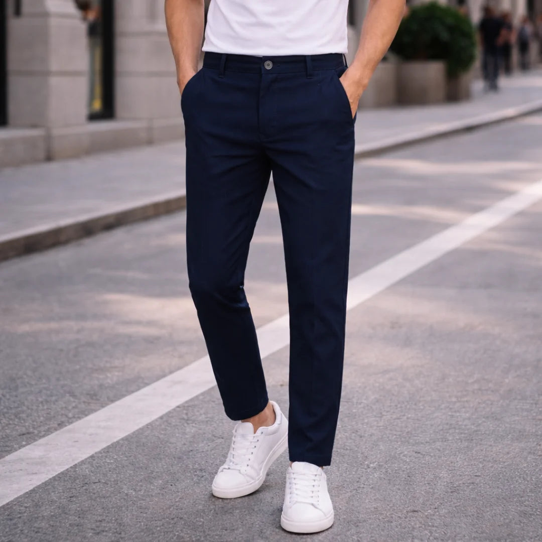 Man wearing Rovarix navy blue straight-fit chino pants with white t-shirt and sneakers walking 