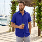 Man wearing Rovarix royal blue short sleeve casual shirt with grey linen shorts holding iced cocktail 
