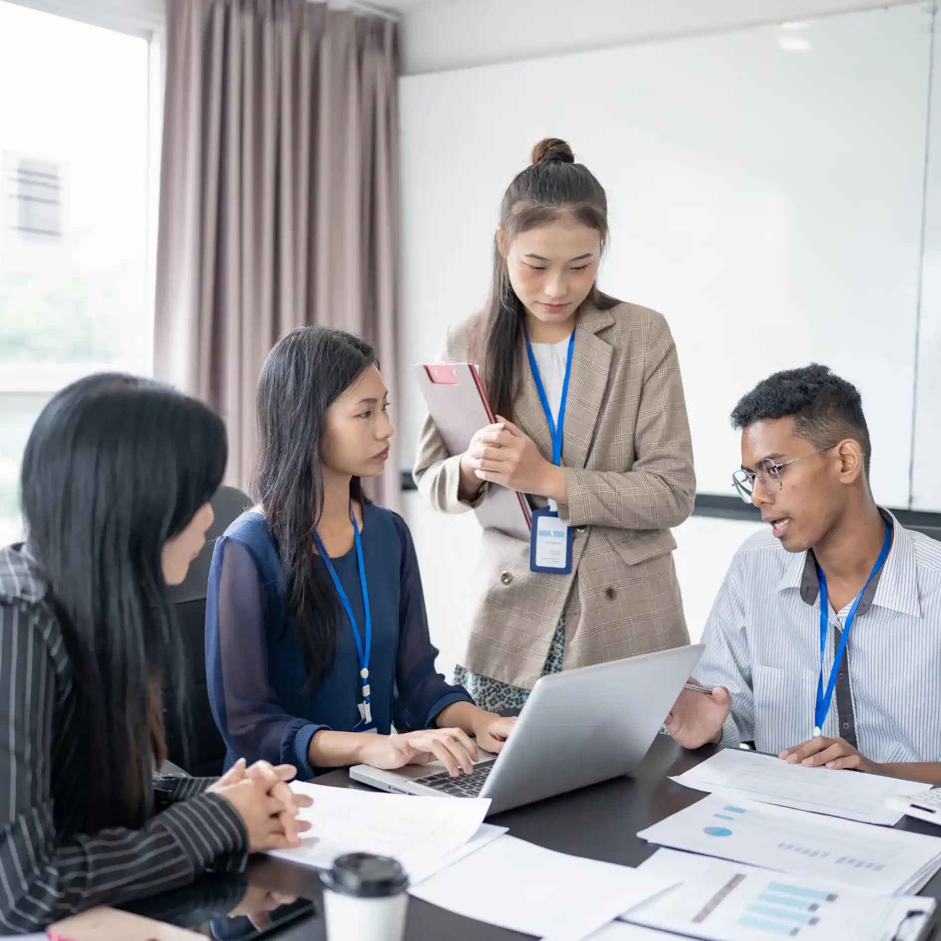 Group of people in a meeting with a laptop and documents on a table.