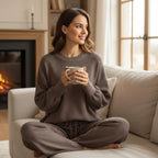 Woman wearing Rovarix taupe waffle knit lounge set sitting on couch by fireplace holding coffee mug