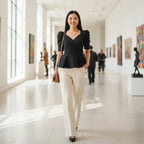 Woman wearing Rovarix black peplum top with puff sleeves and white trousers walking
