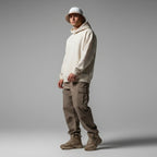 Man wearing Rovarix reversible white bucket hat with beige hoodie and neutral streetwear outfit