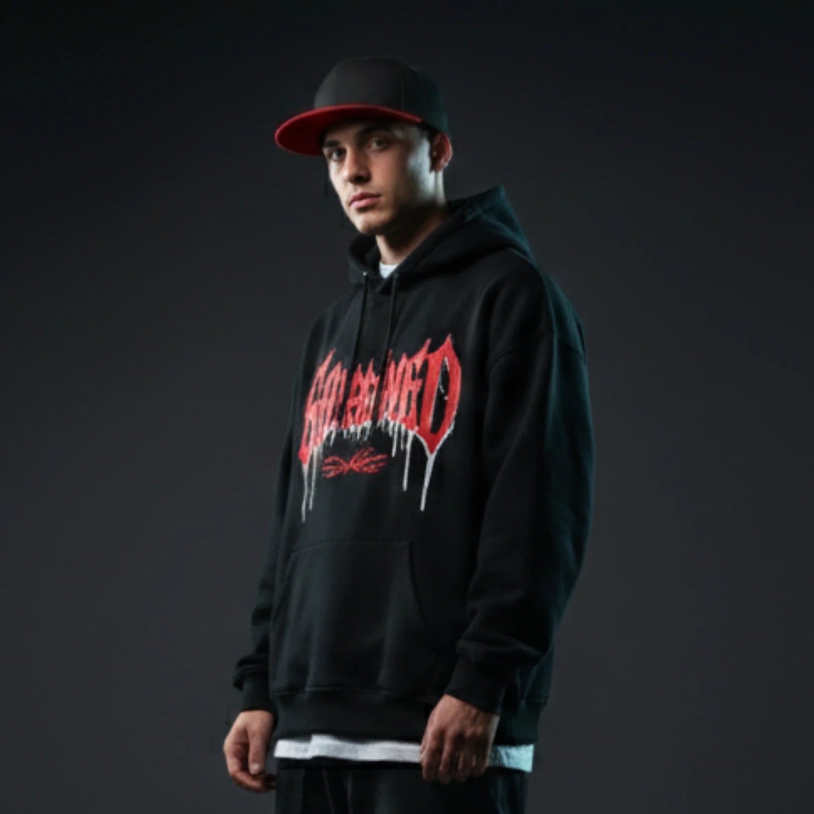Young man wearing Rovarix black and red snapback hat with flat brim and streetwear hoodie