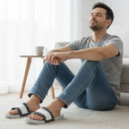 Man wearing Rovarix white slide sandals with black geometric pattern relaxing at home on carpet
