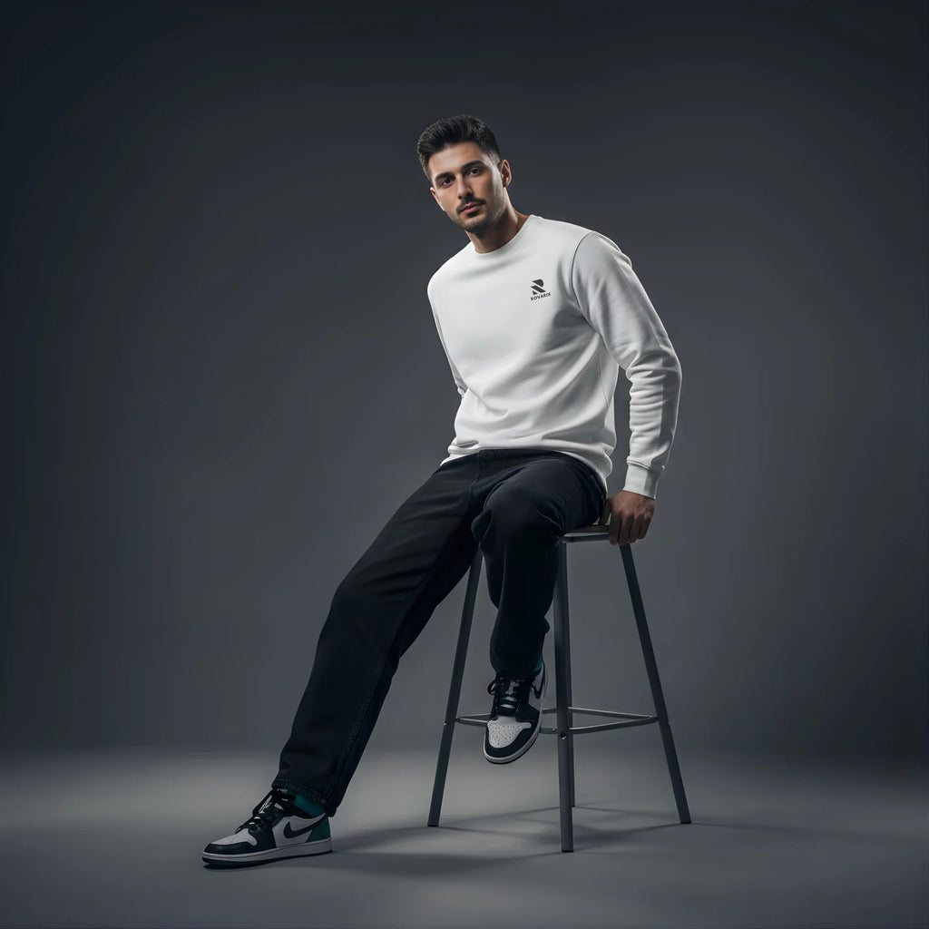 Man sitting on a stool wearing a Rovarix white sweatshirt and black pants against a dark background